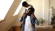 A son rides on his father’s shoulders in their condo.